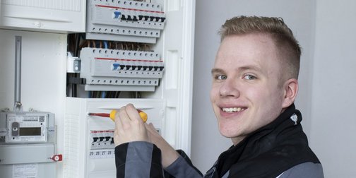 Ein Elektroniker der an einem Verteilerkasten schraubt